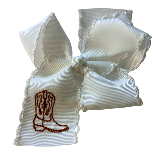 A white ribbon hair bow with a western boot embroidered in finished with a scalloped lace trim.