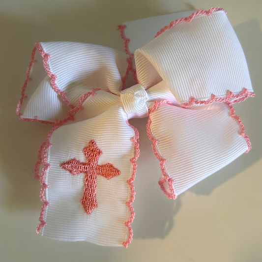 A white ribbed grosgrain ribbon hair bow with pink scalloped trim and a pink embroidered cross 