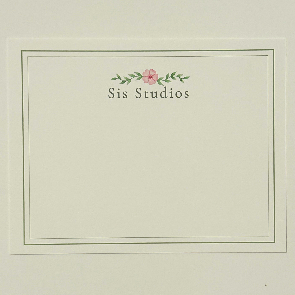 A square cream-colored notecard with a thin double-line border, featuring the text custom personalization with small pink flower and green leaves