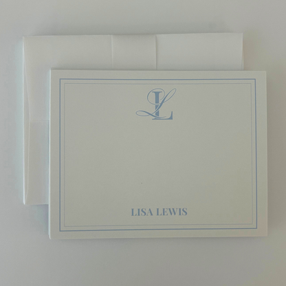A personalized stationery card with a matching envelope, featuring a light blue monogram and name 