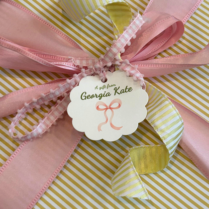 Yellow striped paper, tied with pink and white gingham ribbon, and decorated with a scalloped paper tag personalized