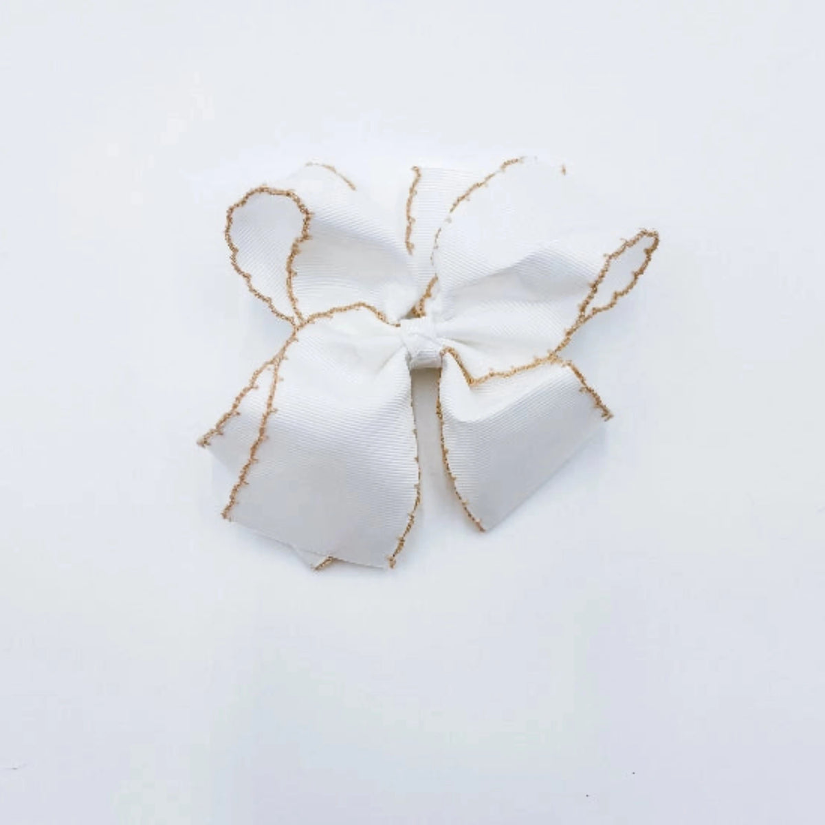A white fabric hair bow with delicate tan trim