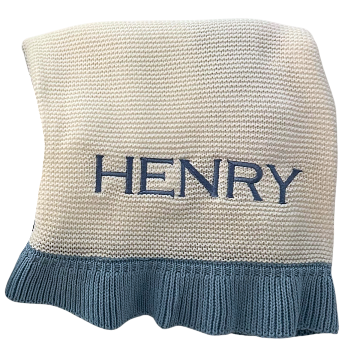 A personalized cream-colored knit baby blanket with a blue ruffled hem and the name embroidered in blue across the front.